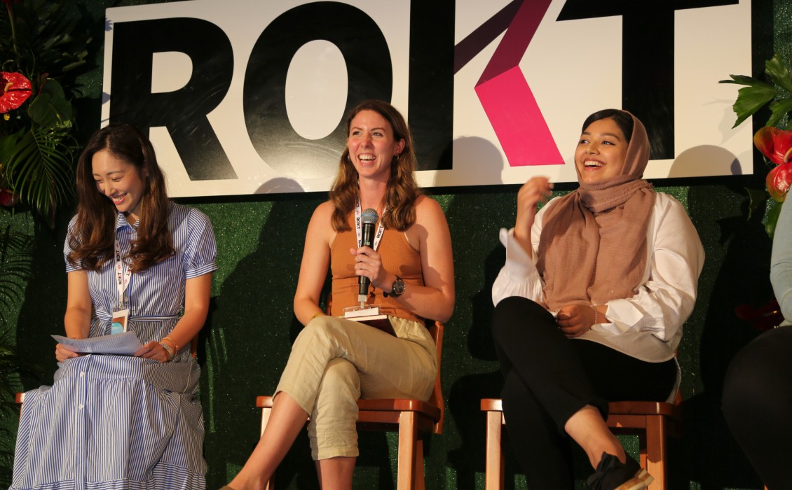 Three Rokt women sitting on a stage holding a conference